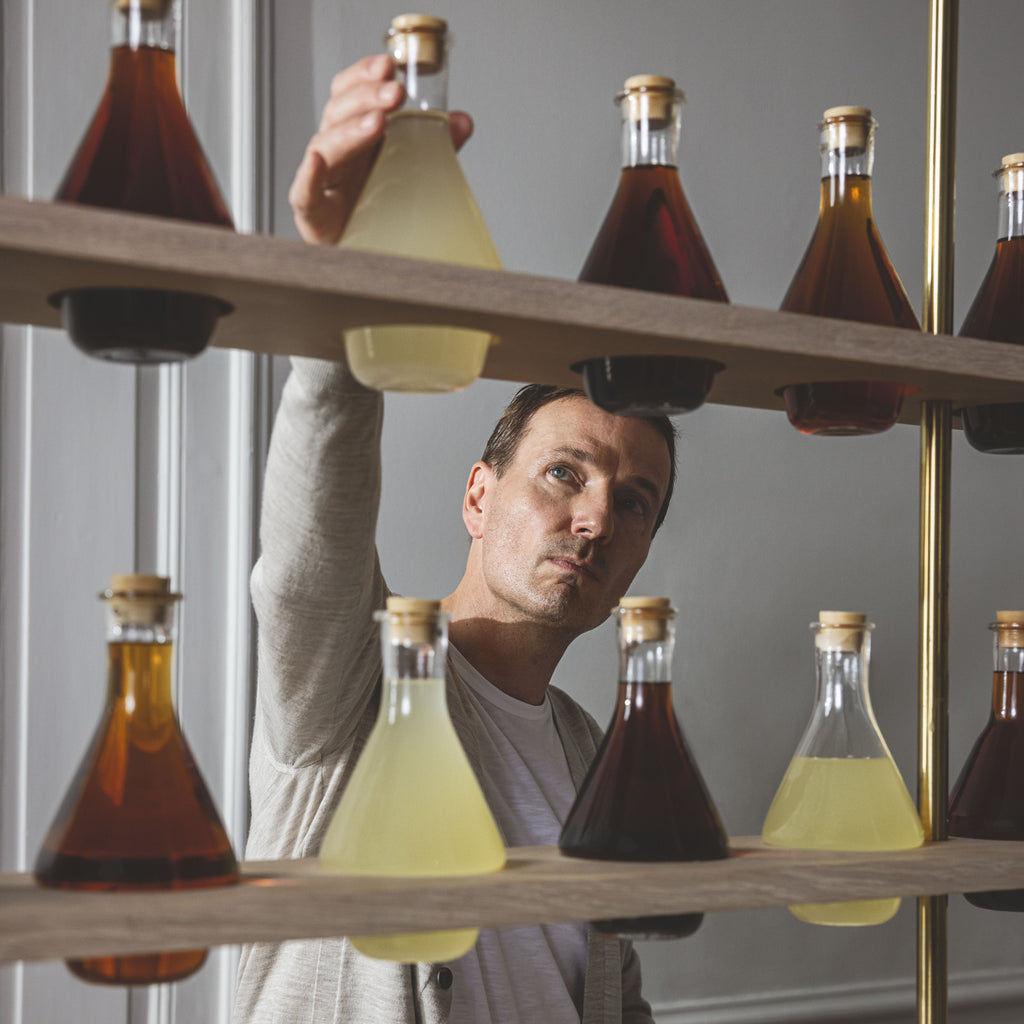 Hårklinikken founder Lars Skjøth reaching for Hair Gain Extract in glass mixing bottle on shelf